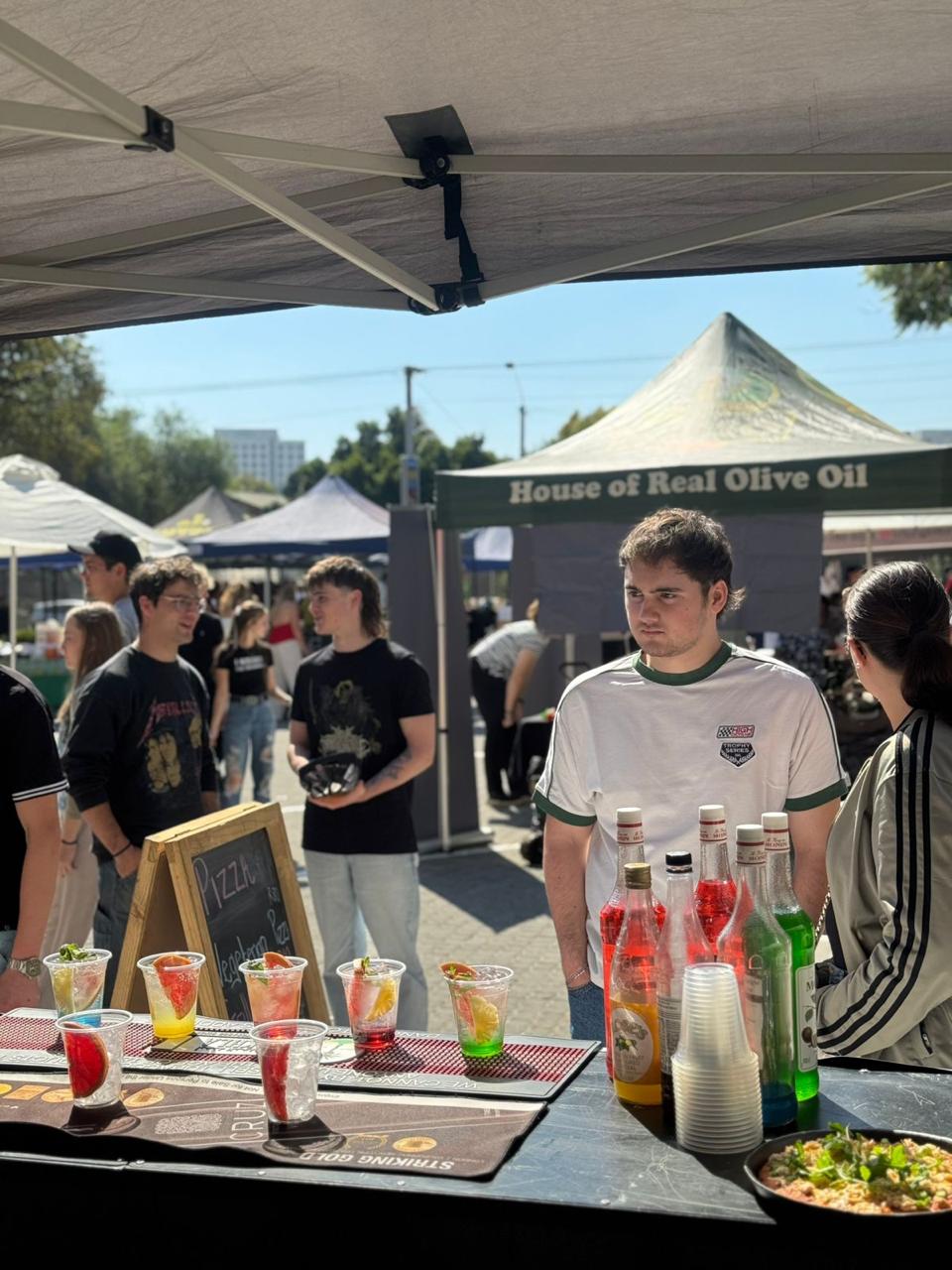 A vintage kombi van converted into a mobile bar, set up at an outdoor event during a beautiful sunset.